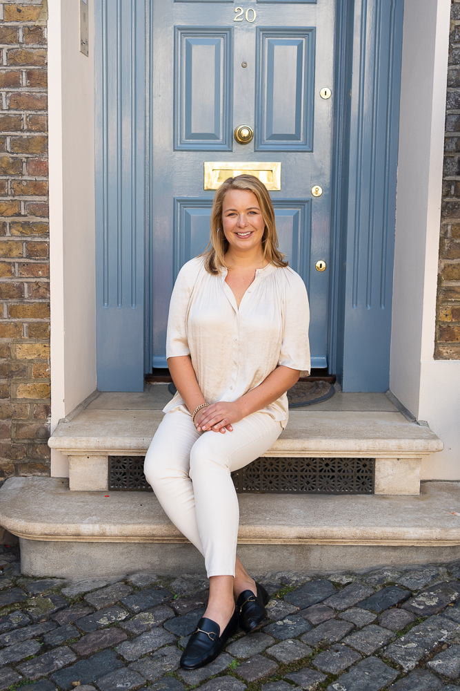 blonde lady sitting on steps in front of blue door
